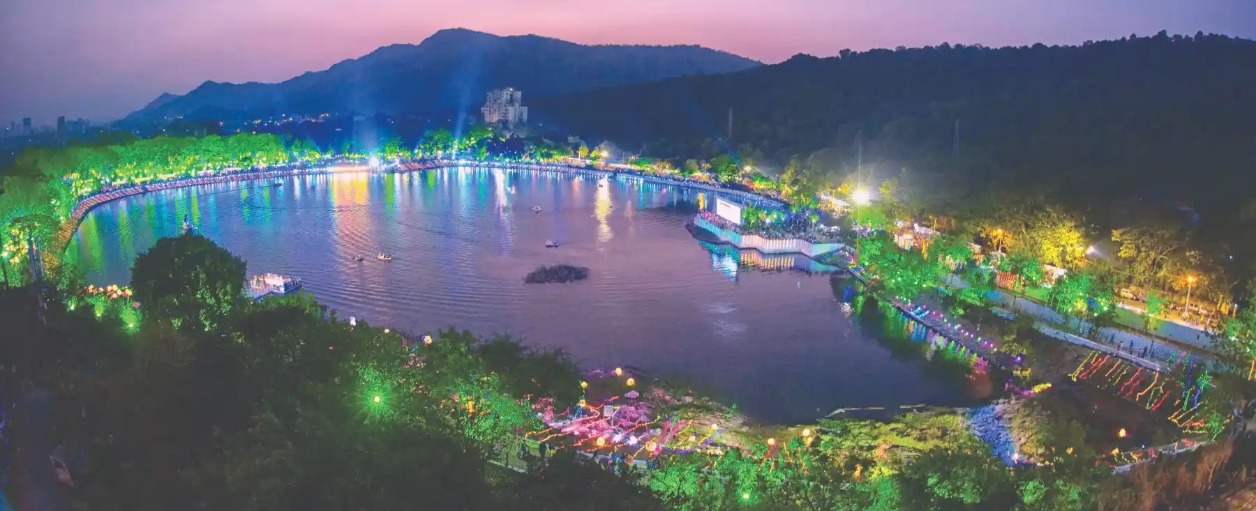 A panoramic view of a lakeside festival lit up at dusk