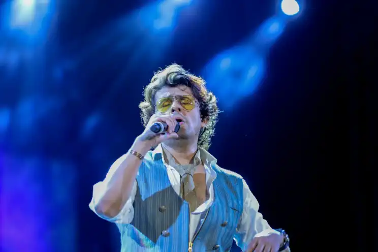 A singer performing live under blue stage lighting