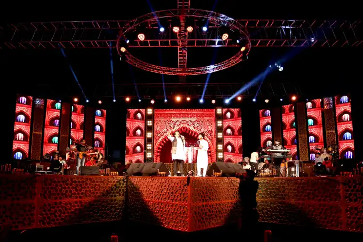 Performers on a large festival stage with an ornate lit backdrop