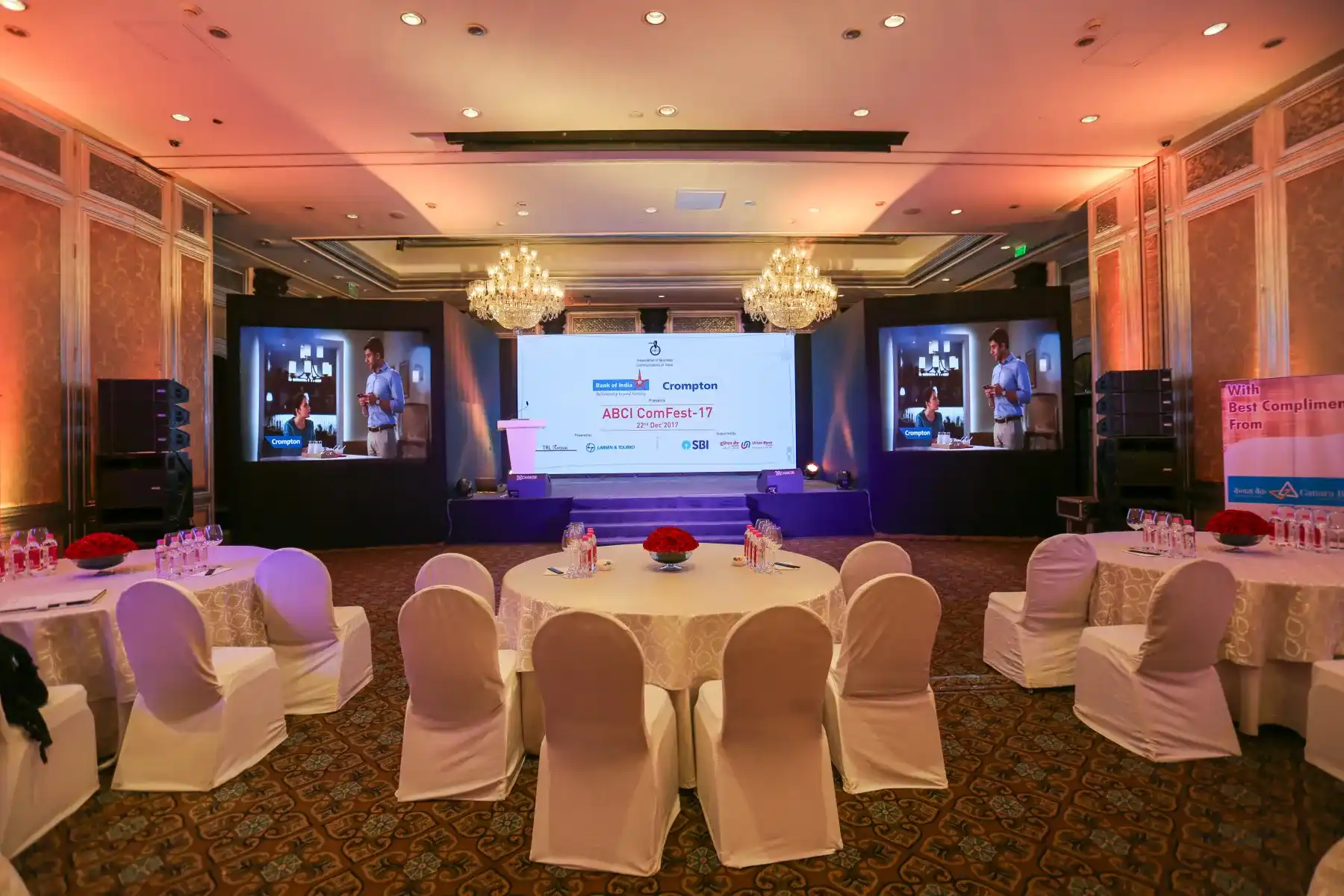 A corporate gala hall with a stage, LED screens and set tables