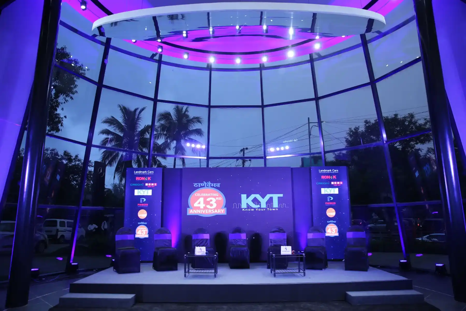 A product launch stage in a glass walled venue with blue lighting