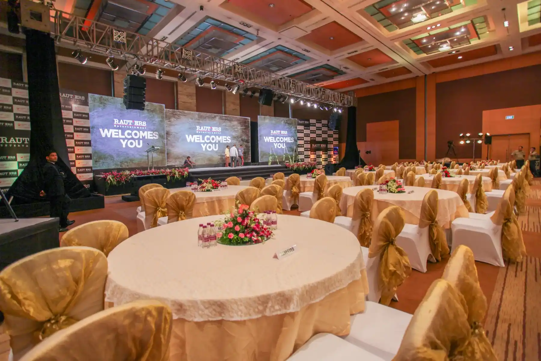 An event hall with LED branding and gold themed guest tables