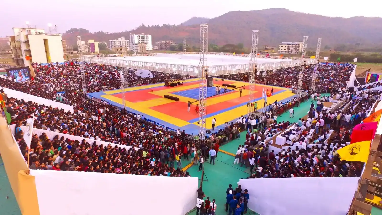 An outdoor sports arena with playing mats and tiered seating
