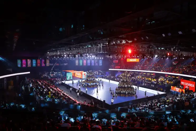 An indoor sports arena lit with stage lighting and a large crowd