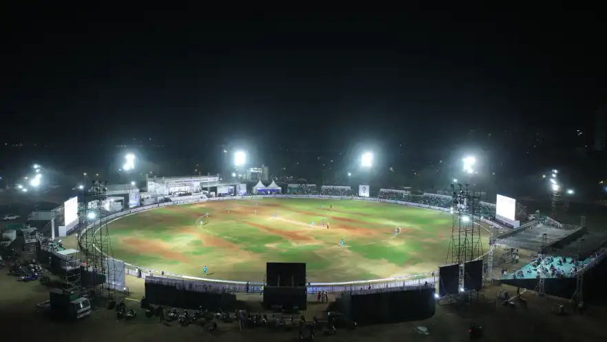 A floodlit cricket stadium at night filled for a match