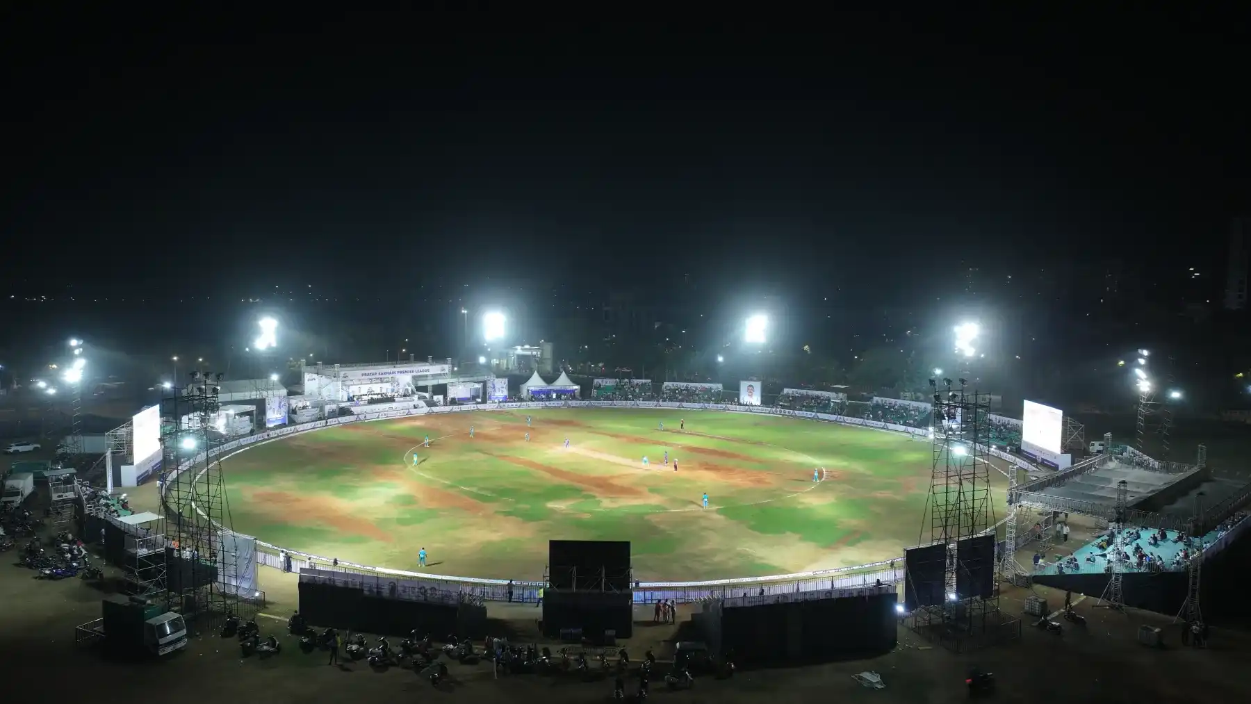 A floodlit cricket stadium at night filled for a match