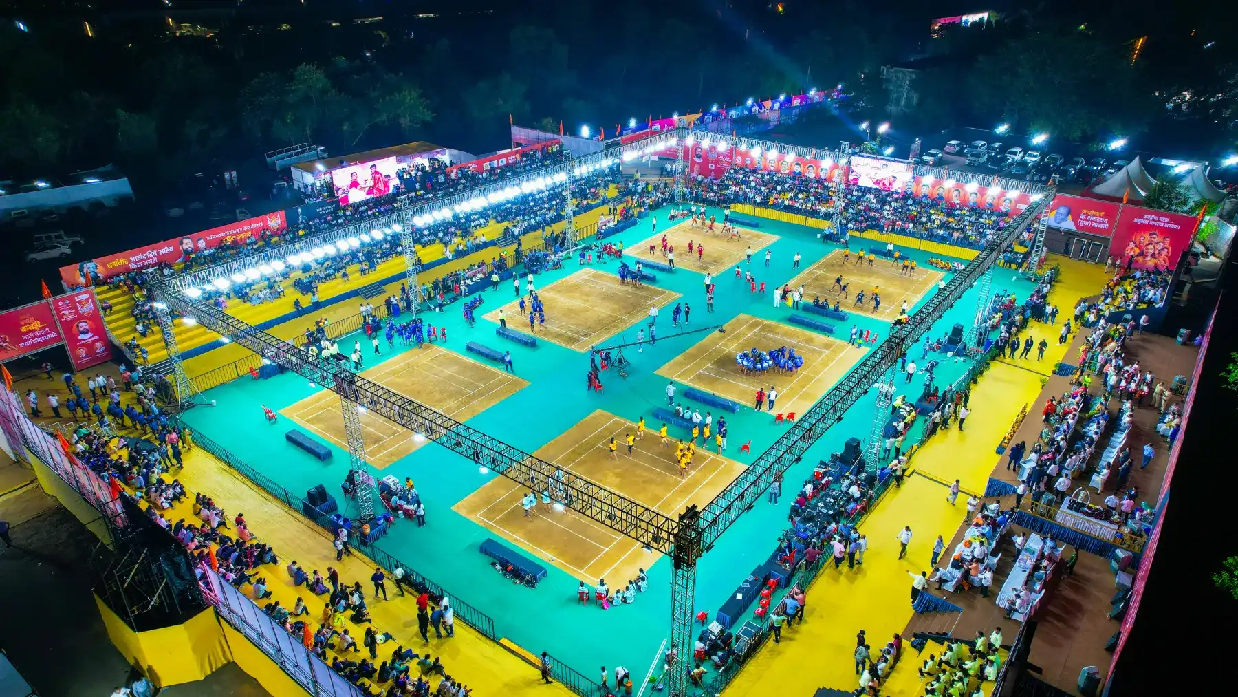 Floodlit kabaddi courts seen from above, with a packed crowd