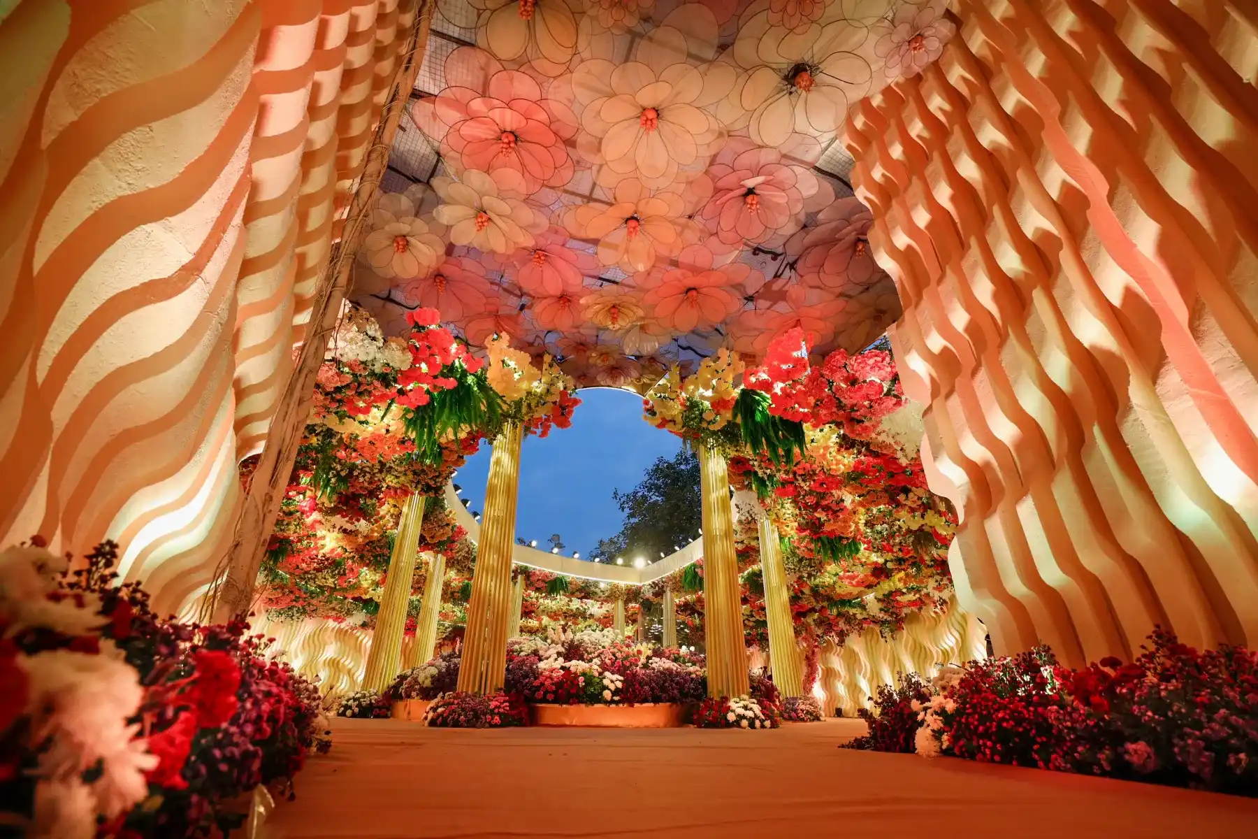 A floral canopy walkway with gold drapes and hanging blooms