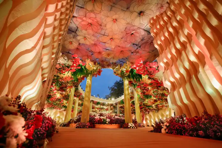A floral canopy walkway with gold drapes and hanging blooms