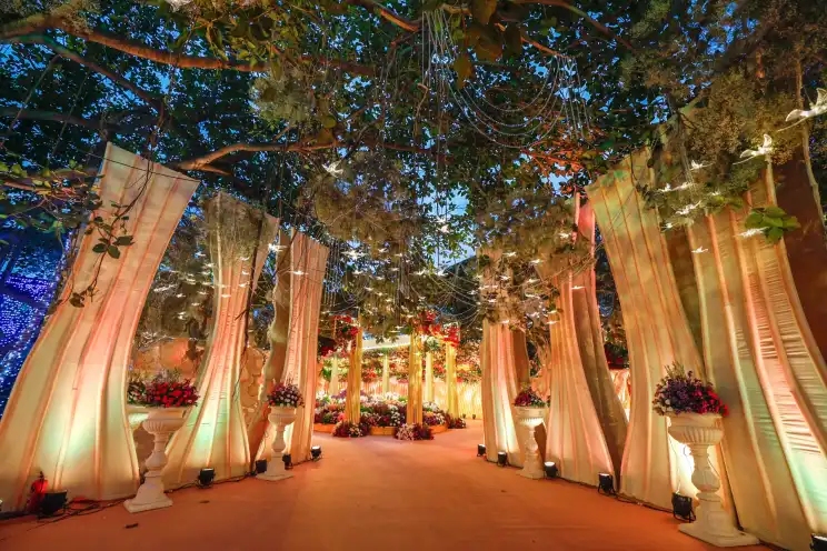 A wedding setup with sweeping draped fabric, florals and warm lighting