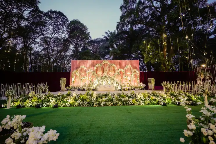 An open air wedding ceremony stage with florals under tall trees