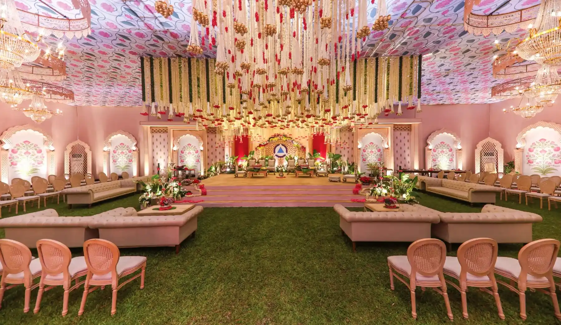 An indoor reception stage in pink and gold with lounge seating